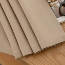 Elsa Naturel kleur verduisterende gordijnen. Onderkant geplooid op tafel. Zichtbaar is de nette afwerking.