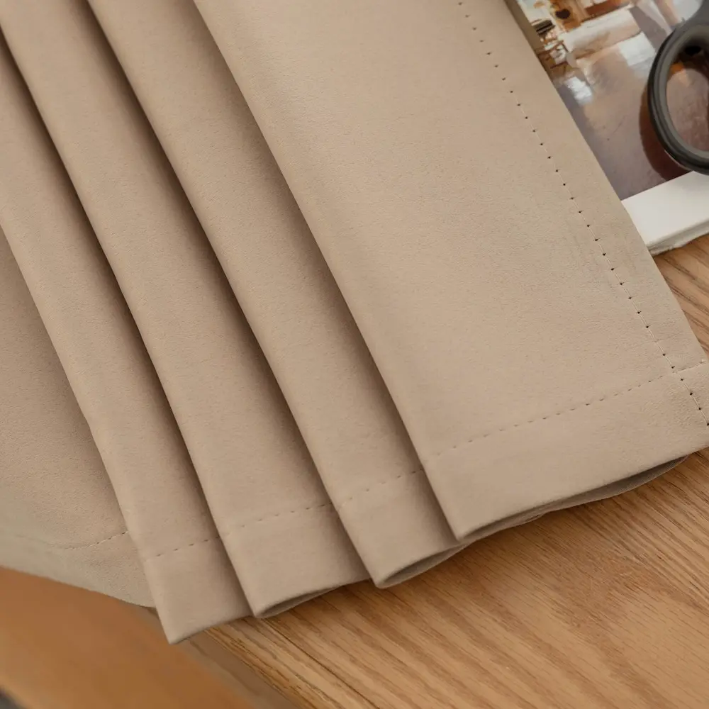 Elsa Naturel kleur verduisterende gordijnen. Onderkant geplooid op tafel. Zichtbaar is de nette afwerking.