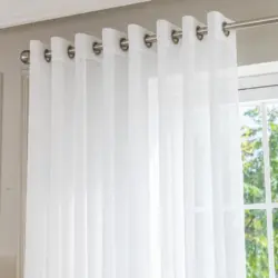 Helder witte Bibiana vitrage met matte roestvrij stalen ringen aan een zilverkleurige roede voor een zonnig raam